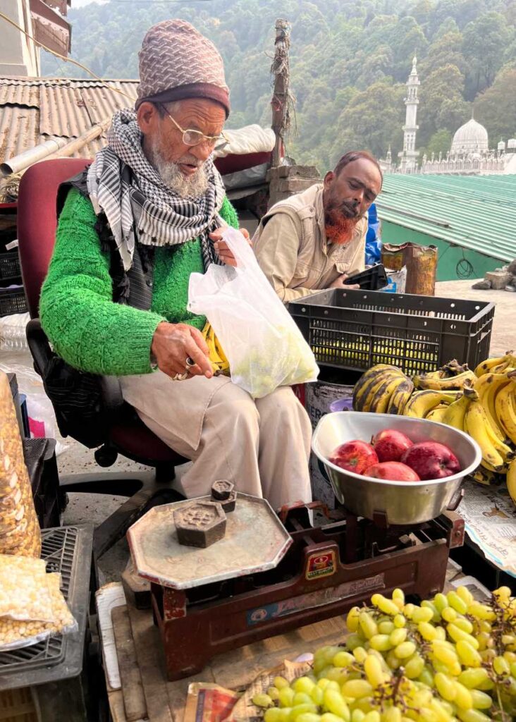 Un hombre indio pesando la fruta para venderla.